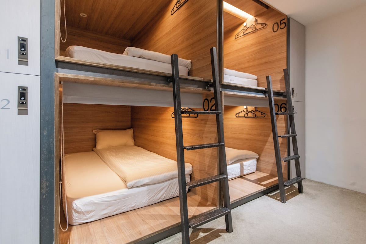A bunk bed room with wooden walls, numbered beds, and a ladder.