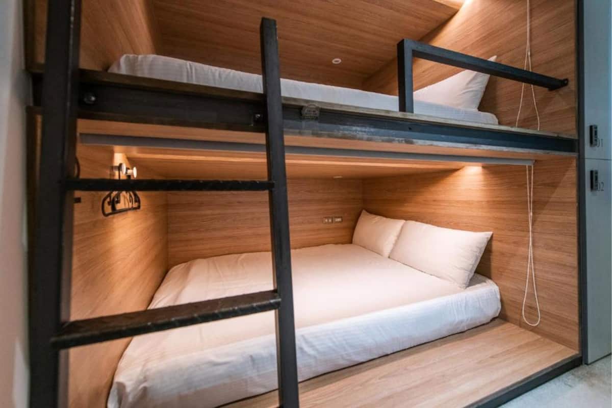 A bunk bed with a wooden interior and a single bed below.