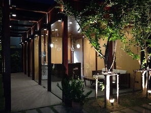 Un patio al aire libre con una pérgola de madera, asientos y plantas en macetas.
