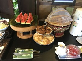 Un bufé de desayuno con rebanadas de sandía, muffins, pasteles y una máquina de café.