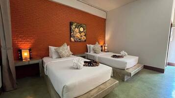 A hotel room with two beds, a brick accent wall, and a painting.