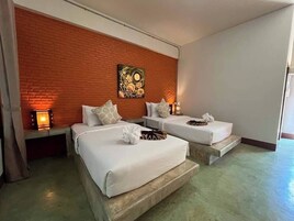 Habitación de hotel con dos camas, una pared de ladrillo decorativa y un cuadro.