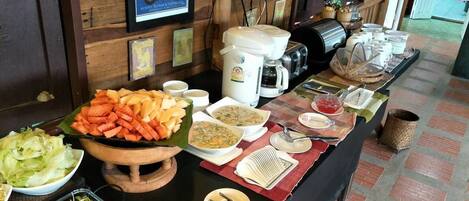 A buffet table with various food items and utensils, set against a wooden wall with framed pictures.