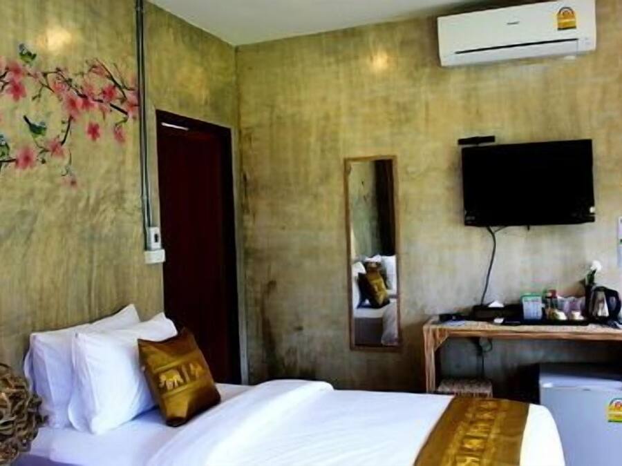 Quarto de hotel com cama, escrivaninha, televisão e ar condicionado.