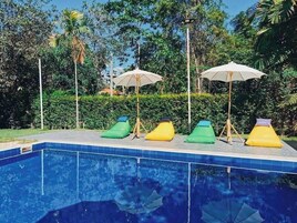 Una piscina con sillones de playa y sombrillas.