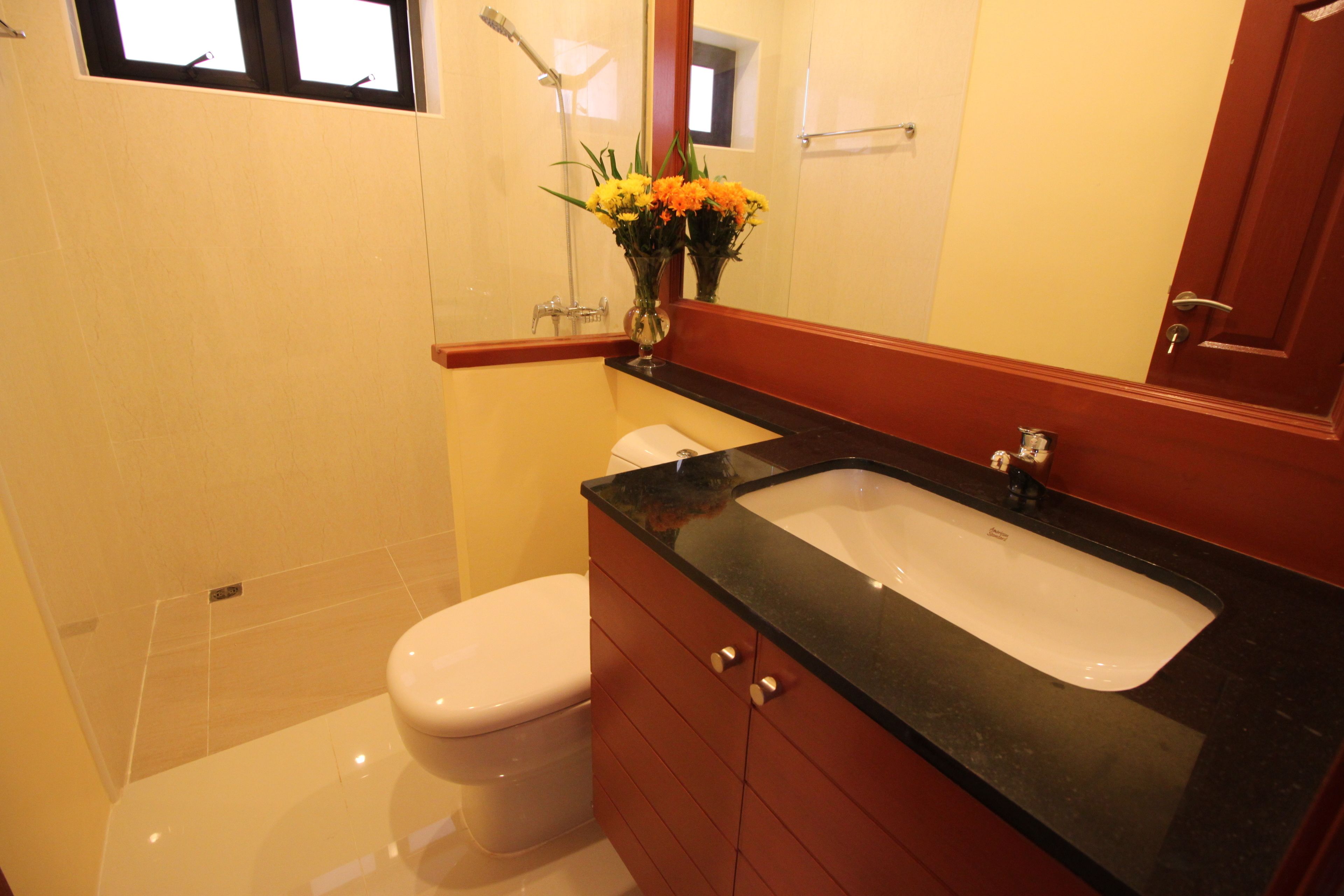 A bathroom with a white toilet, a black sink, and a mirror above the sink.
