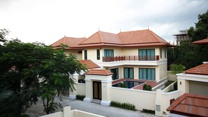 A multi-story residential building with a tiled roof, a balcony, and a swimming pool. - Bang Saray Pool Villa by Pattaya Sunny Rentals (Sattahip)