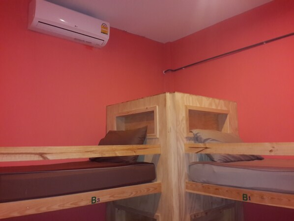 A room with two bunk beds labeled B3 and B1, a red wall, and an air conditioning unit.