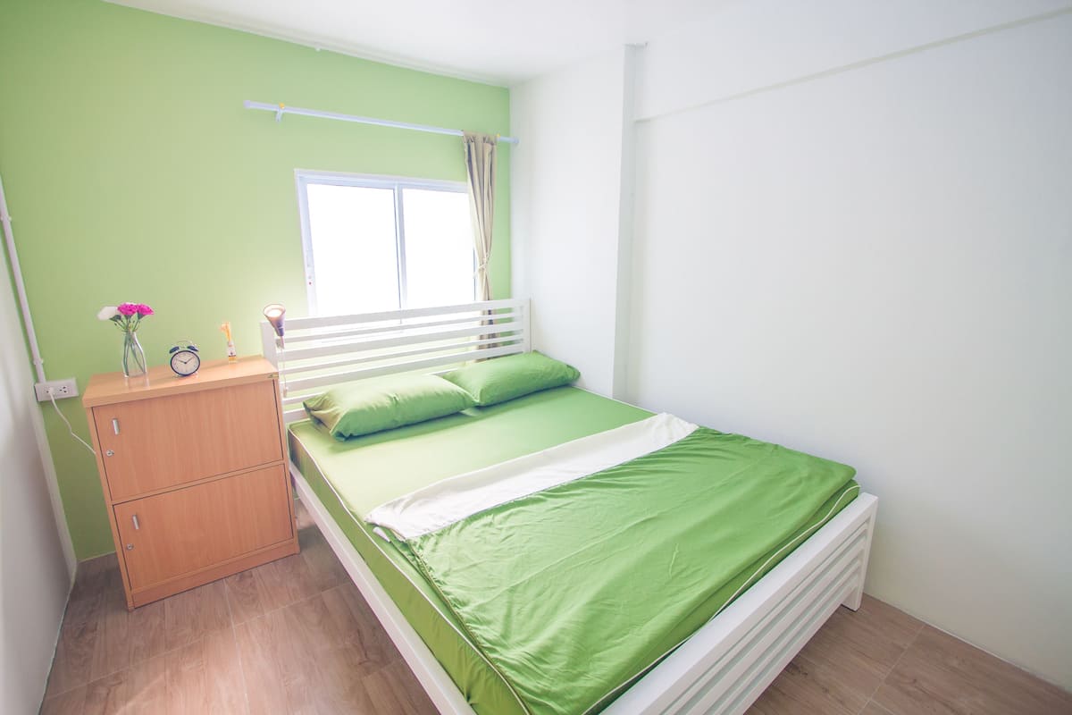 Une chambre à coucher comprenant un lit, une table de chevet, une fenêtre et une étagère fixée au mur.