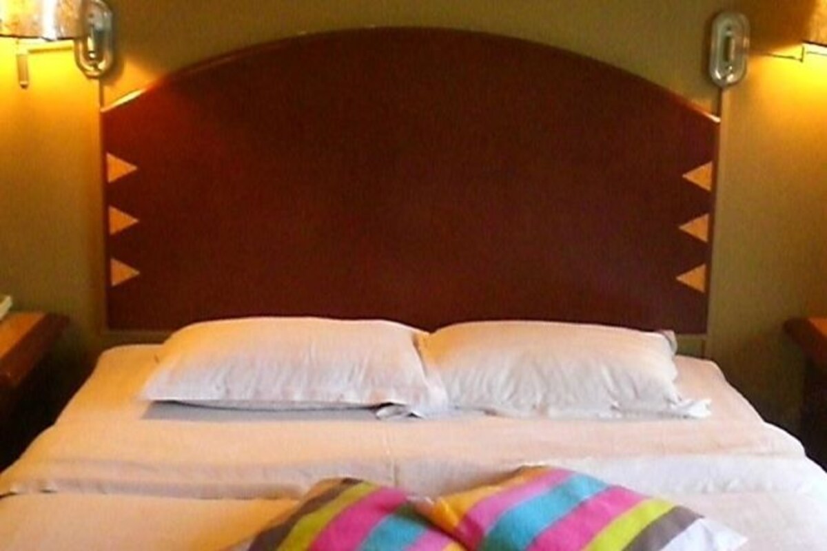 Una habitación de hotel con una cama grande, dos mesitas de noche y un cabecero de madera.
