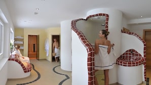 Ein modernes Badezimmer mit geschwungenem Design, einem großen Spiegel und einer Sitzecke.