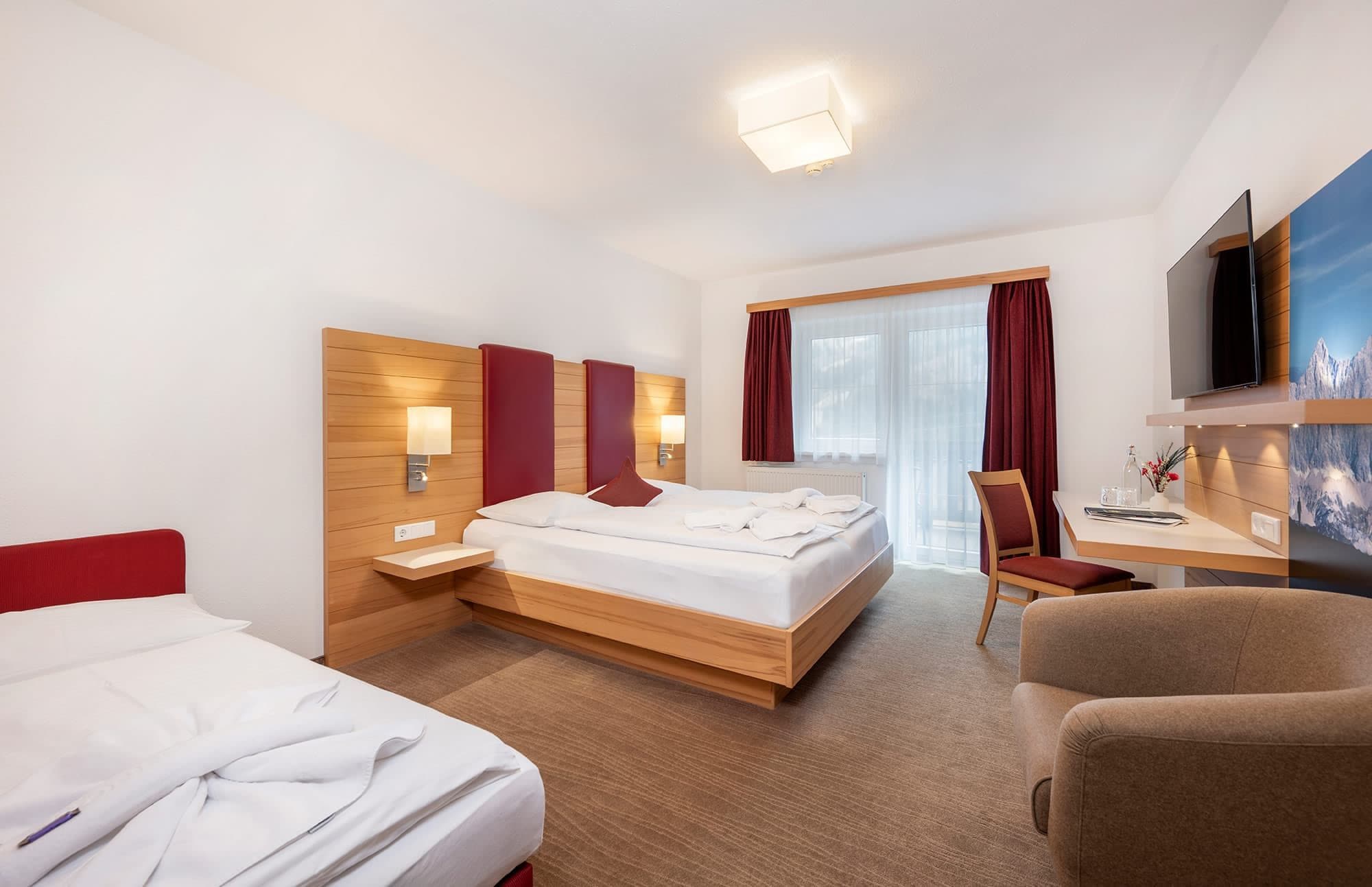 Une chambre d’hôtel avec un lit, un bureau, une chaise et un téléviseur.