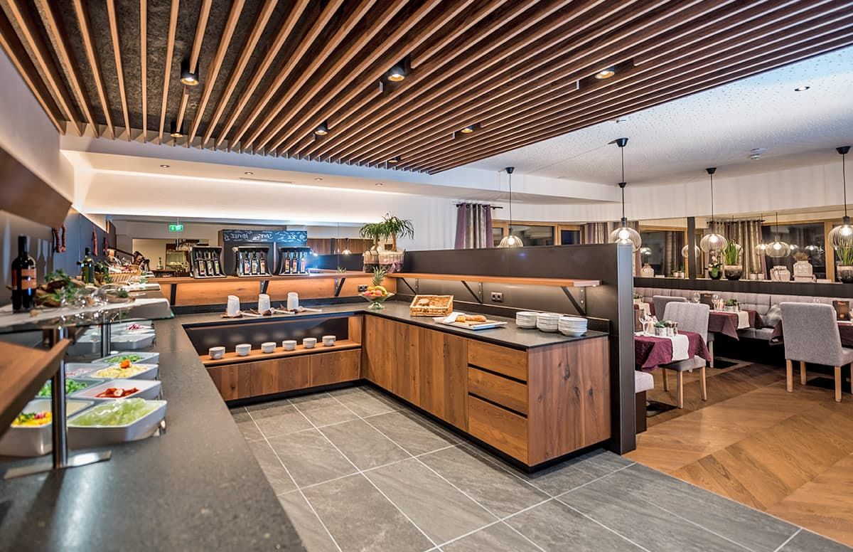 Un restaurante moderno con una isla central, detalles de madera y una zona de bar.