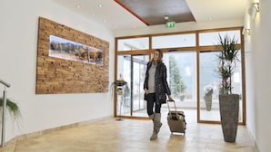 A spacious lobby with a wooden wall art, a large potted plant, and a glass door leading outside.