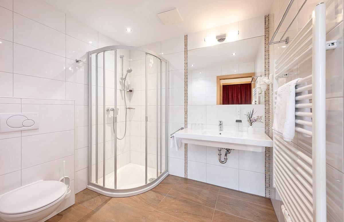 A modern bathroom with a glass-enclosed shower, a white sink, and a toilet.