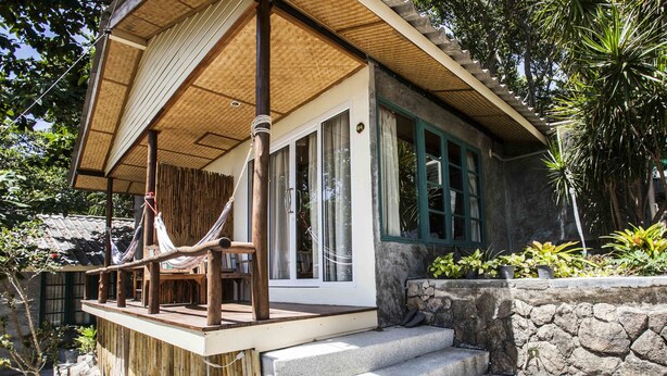 A house with a wooden deck, a stone wall, and a hammock. - Bubble Bungalow (Koh Tao)
