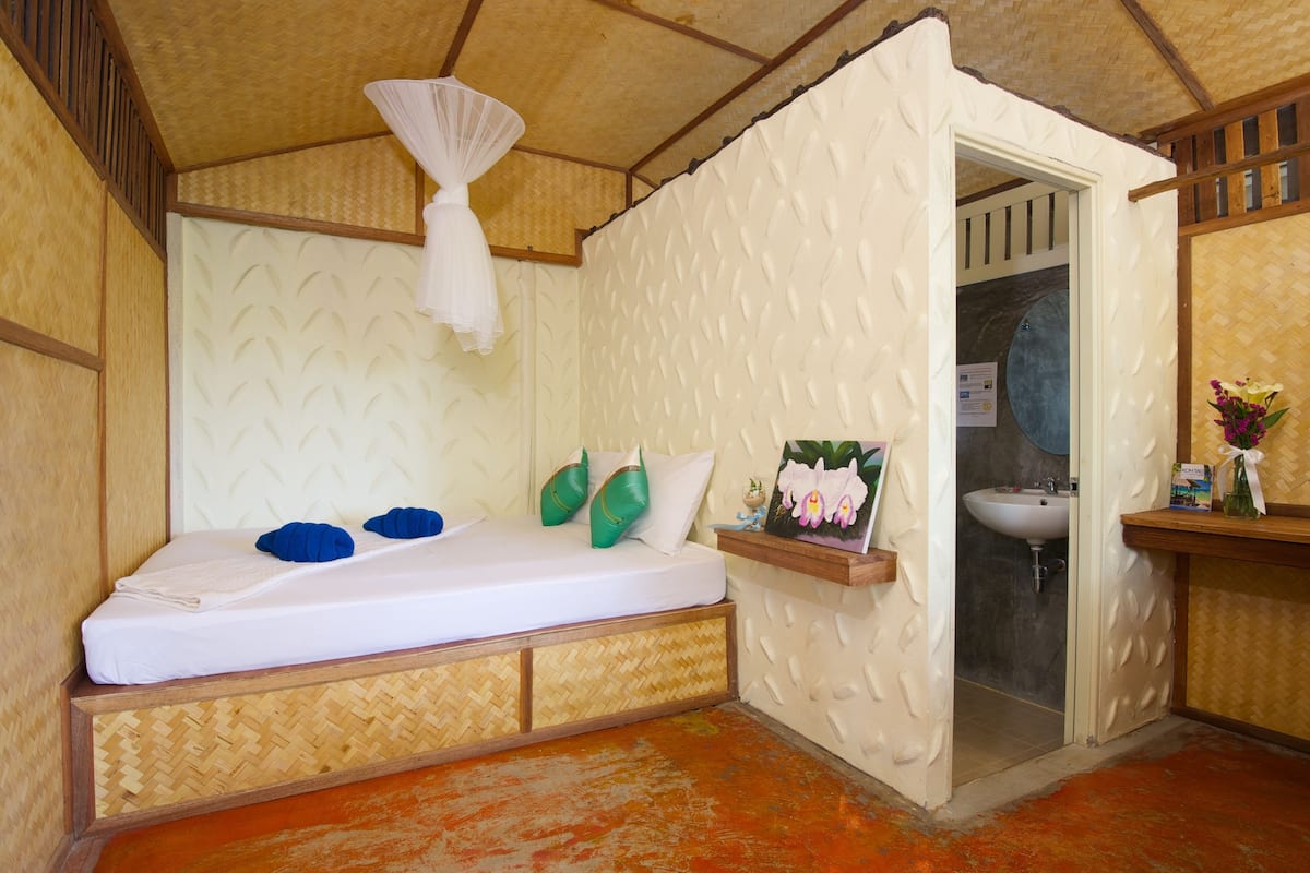A room with a bed, a small shelf with toiletries, and a bathroom door.