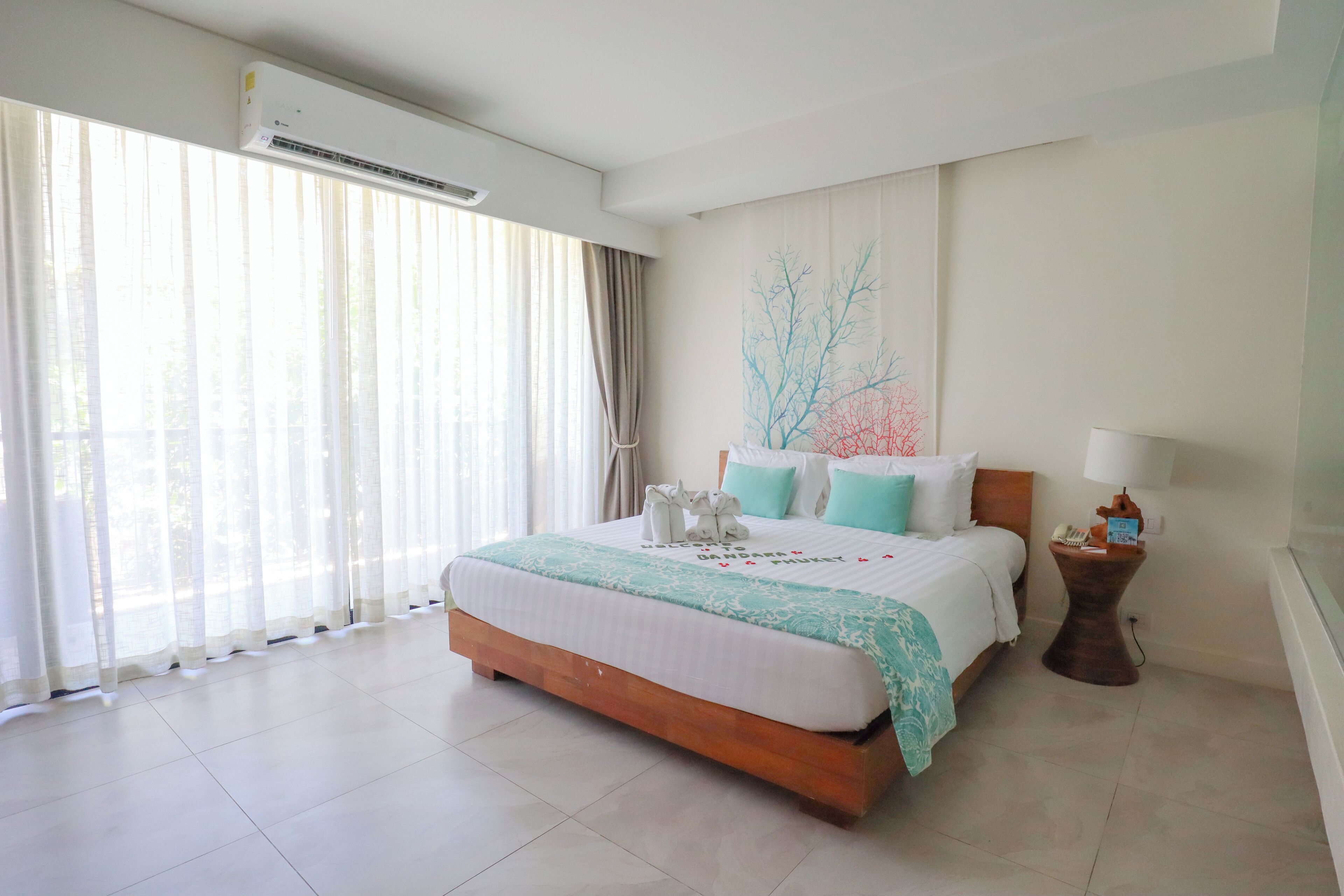 A hotel room with a large bed, a bedside table with a lamp, and a wall-mounted air conditioner.