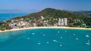 A coastal town with a beach, boats, and buildings. - Bandara Beach Resort, Phuket (Wichit)