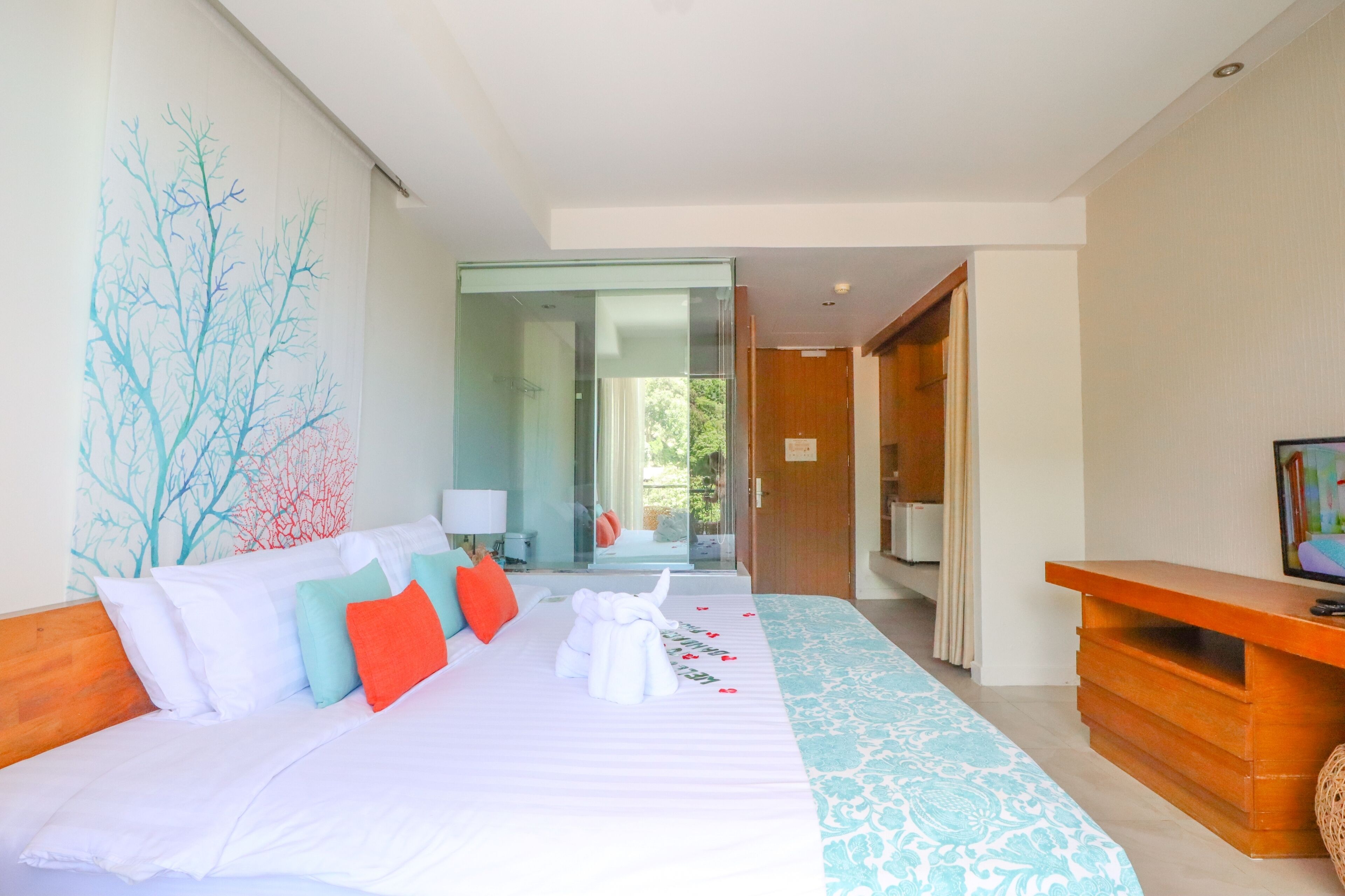 A hotel room with a large bed, a wooden headboard, a television, and a view of the outdoors.
