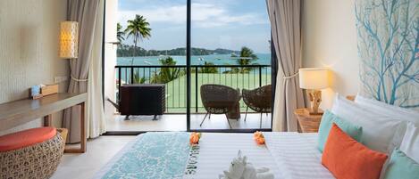 A hotel room with a large bed, a balcony with chairs, and a view of the sea.
