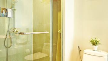 A modern bathroom with a glass-enclosed shower, a white toilet, and a towel rack with folded towels.