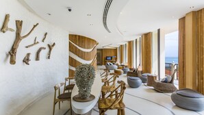 A modern interior with a curved ceiling, wooden wall decor, and a seating area with a view of the sea. - Bandara Beach Resort, Phuket (Wichit)