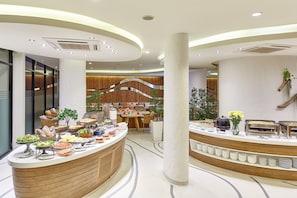 A buffet area with various food items and a seating area with wooden panels and plants. - Bandara Beach Resort, Phuket (Wichit)