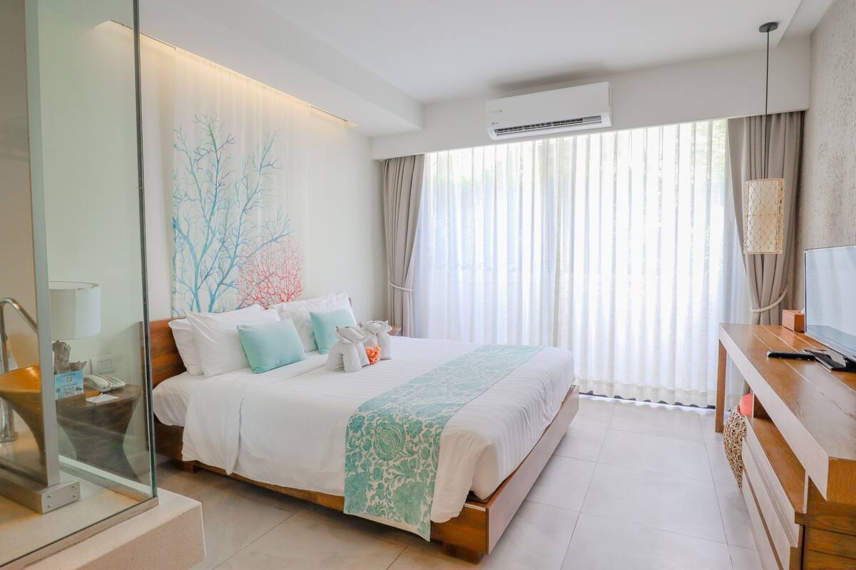 A modern hotel room with a large bed, a desk, and a TV.