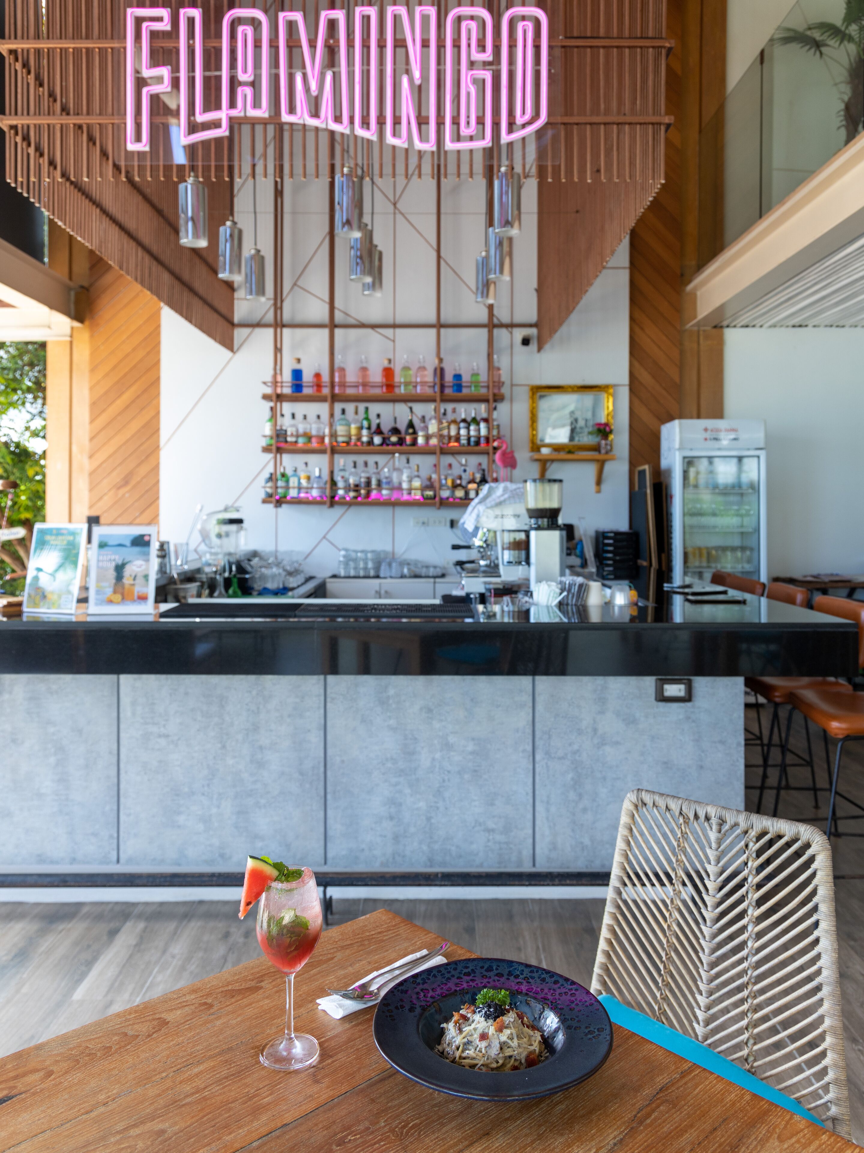A restaurant interior with a bar area, a counter, and a dining table with a plate of food and a drink.