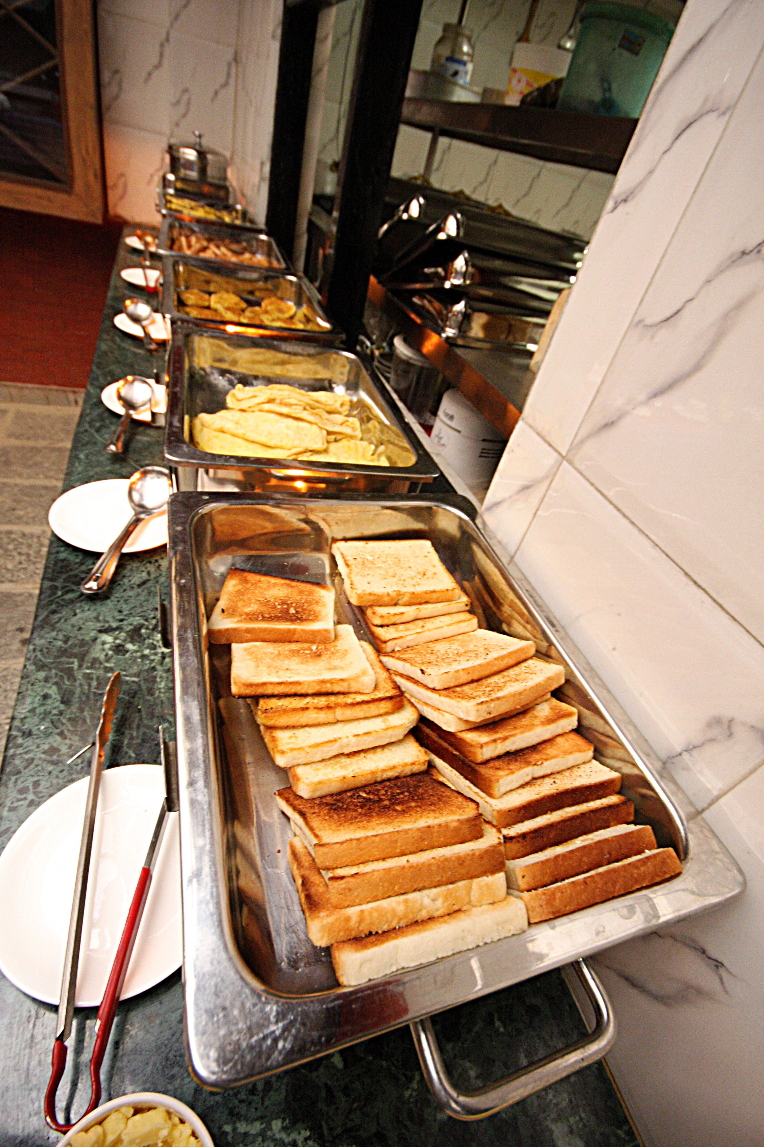 A buffet line with various food items including toast and other dishes.