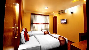 A hotel room with two beds, a television, an air conditioning unit, and a wooden door. - Hotel Bubo Himalaya (Kathmandu)