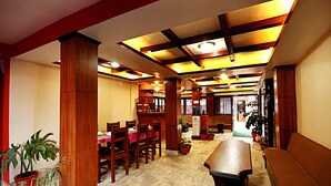 A spacious dining area with wooden furniture, a long table, and potted plants. - Hotel Bubo Himalaya (Kathmandu)