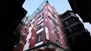 A multi-story hotel with a red and white facade, multiple balconies, and a sign indicating it is a hotel. - Hotel Bubo Himalaya (Kathmandu)