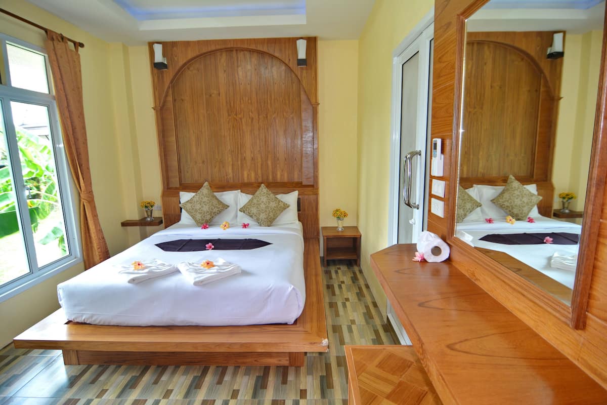 A spacious bedroom with a large bed, wooden headboard, bedside tables, and a large mirror.