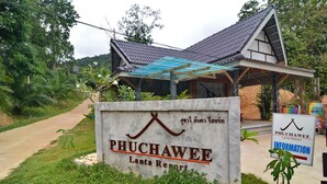Schild für das Phuchawee Lanta Resort mit traditionellem Thai-Dach und überdachter Einfahrt.