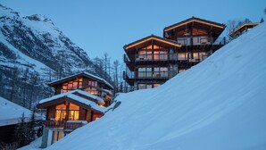 A multi-level wooden chalet with balconies, set against a snowy mountain backdrop. - Chalet A la Casa (Zermatt)