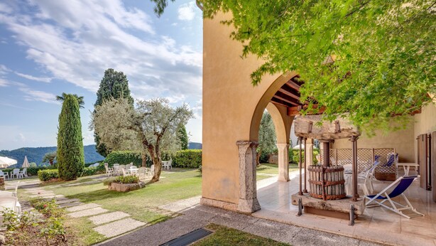 A courtyard with a pergola, outdoor seating, and a view of the landscape. - Residence La Filanda (Costermano sul Garda)