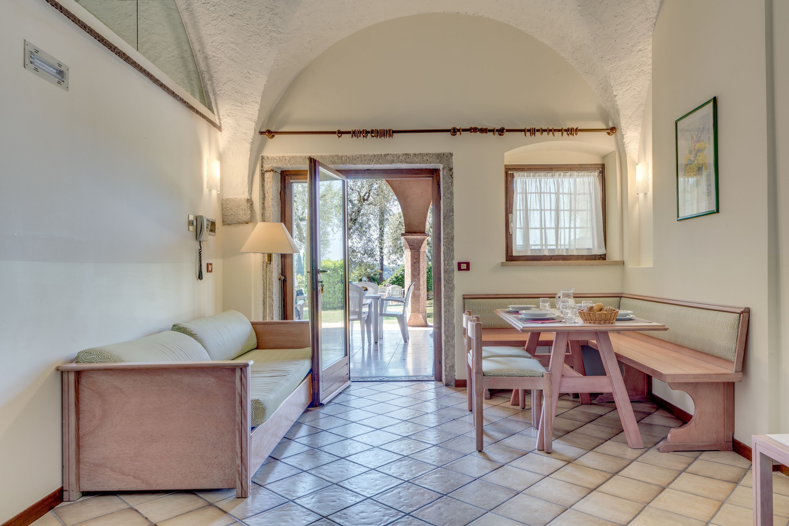 Une pièce confortable avec un canapé, un banc, une table à manger et une vue sur l’extérieur.