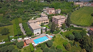 An aerial view of a residential area with a swimming pool surrounded by lush greenery and multiple buildings. - Residence La Filanda (Costermano sul Garda)