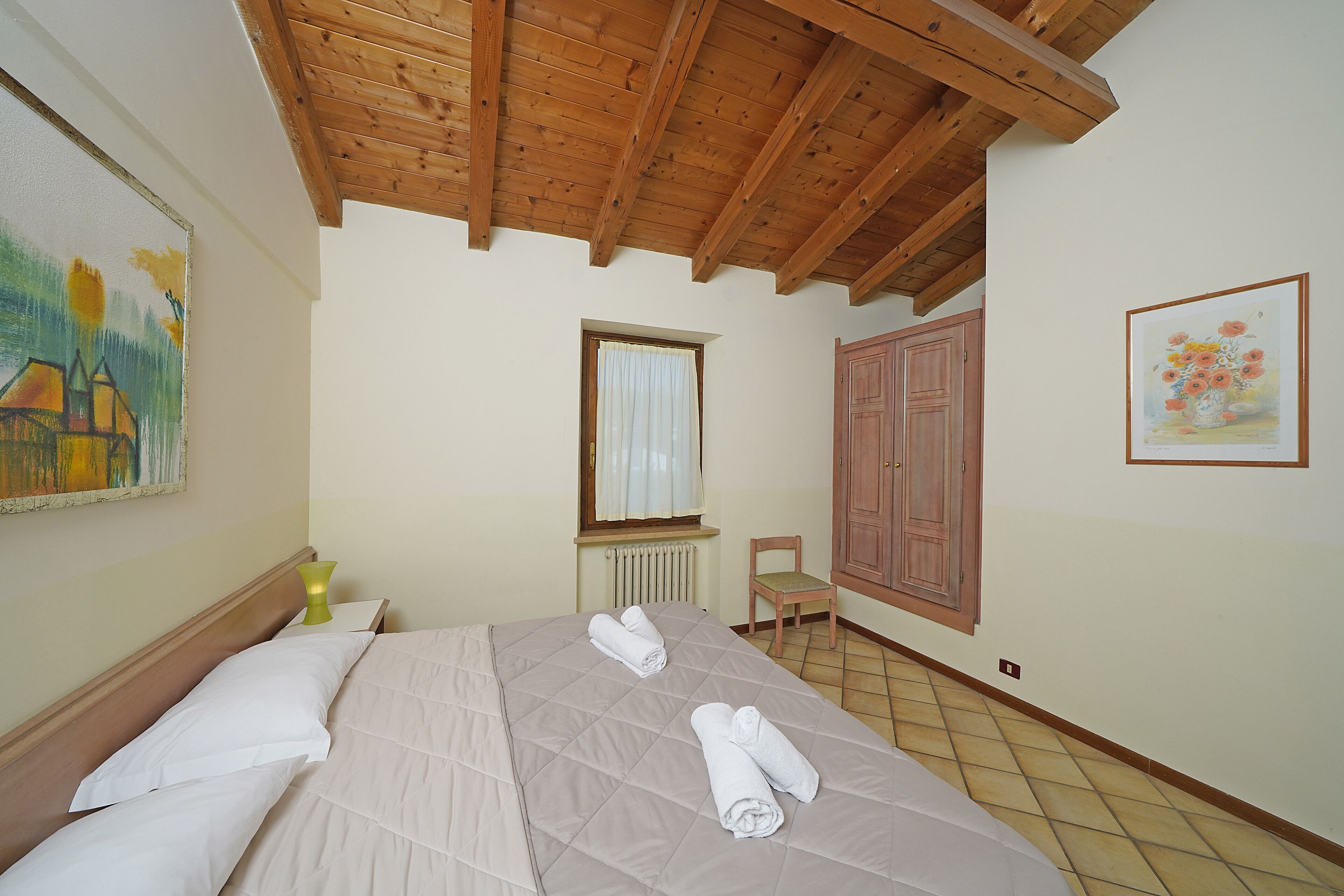 A bedroom with a bed, a chair, a radiator, and a window.