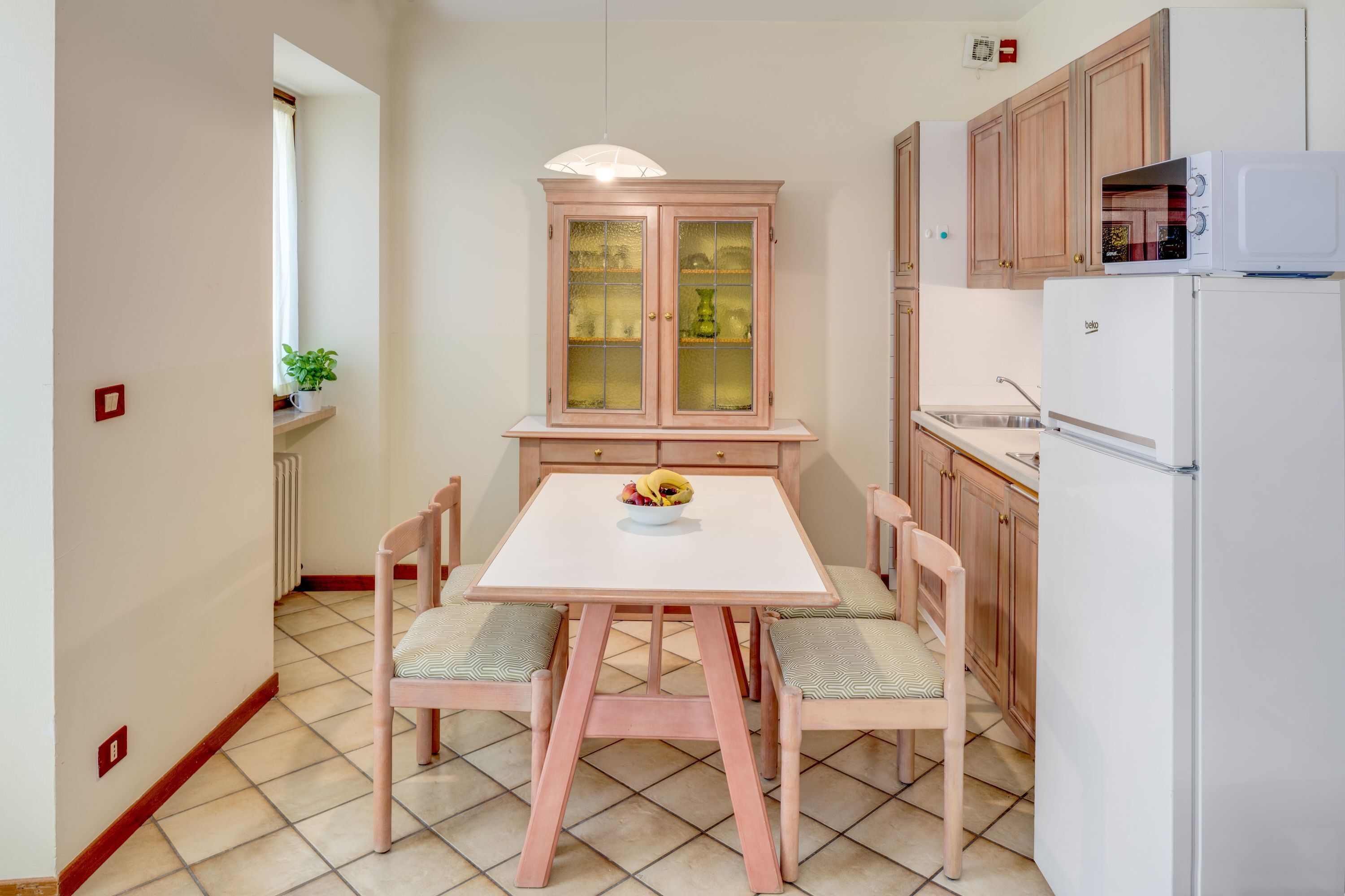 Une cuisine de taille réduite comprenant une table à manger, des chaises, un meuble et un réfrigérateur.