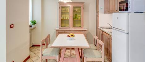 Une cuisine de taille réduite comprenant une table à manger, des chaises, un meuble et un réfrigérateur.