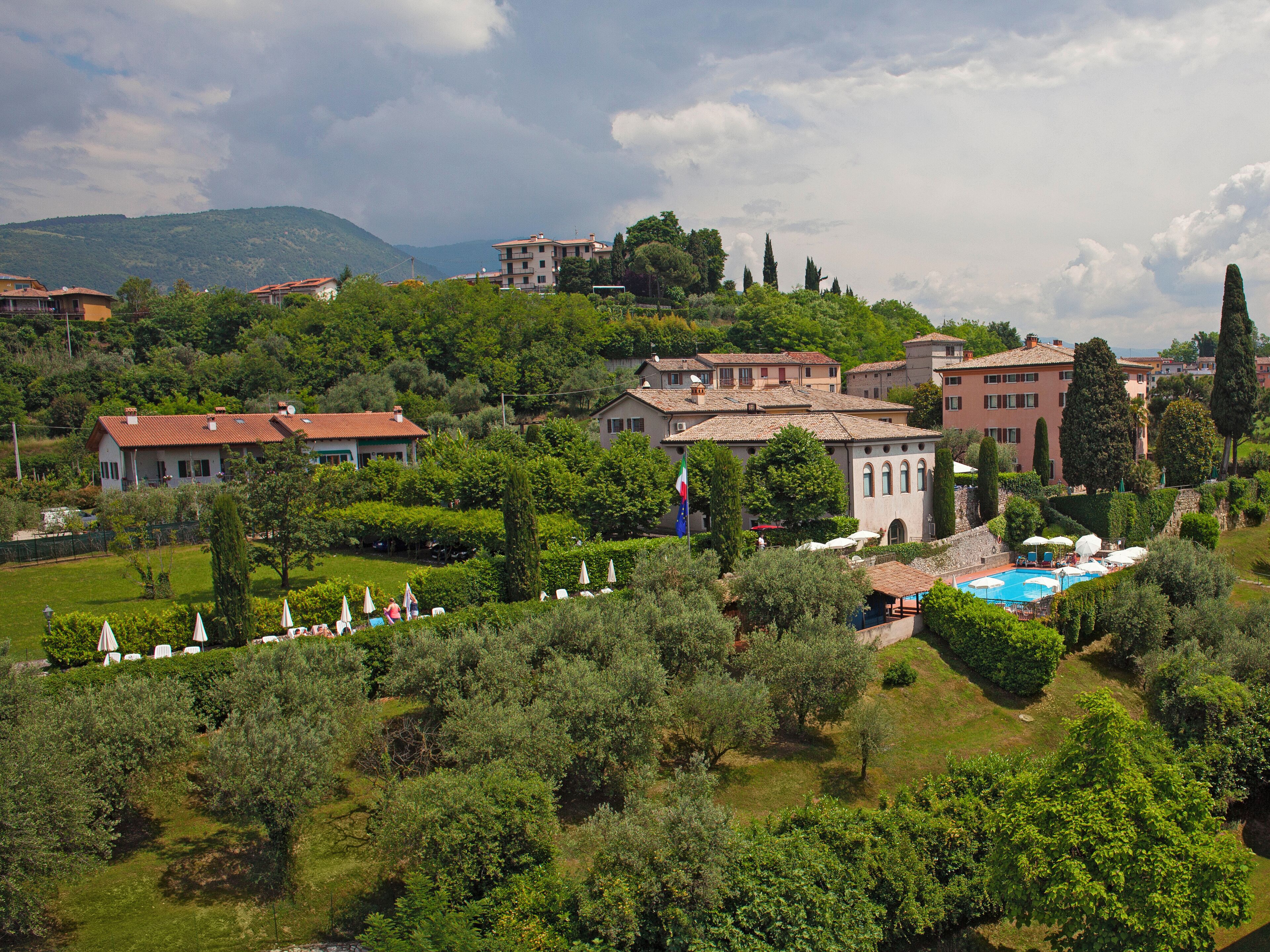 Une villa avec piscine, entourée d’une végétation luxuriante et avec des collines en arrière-plan.