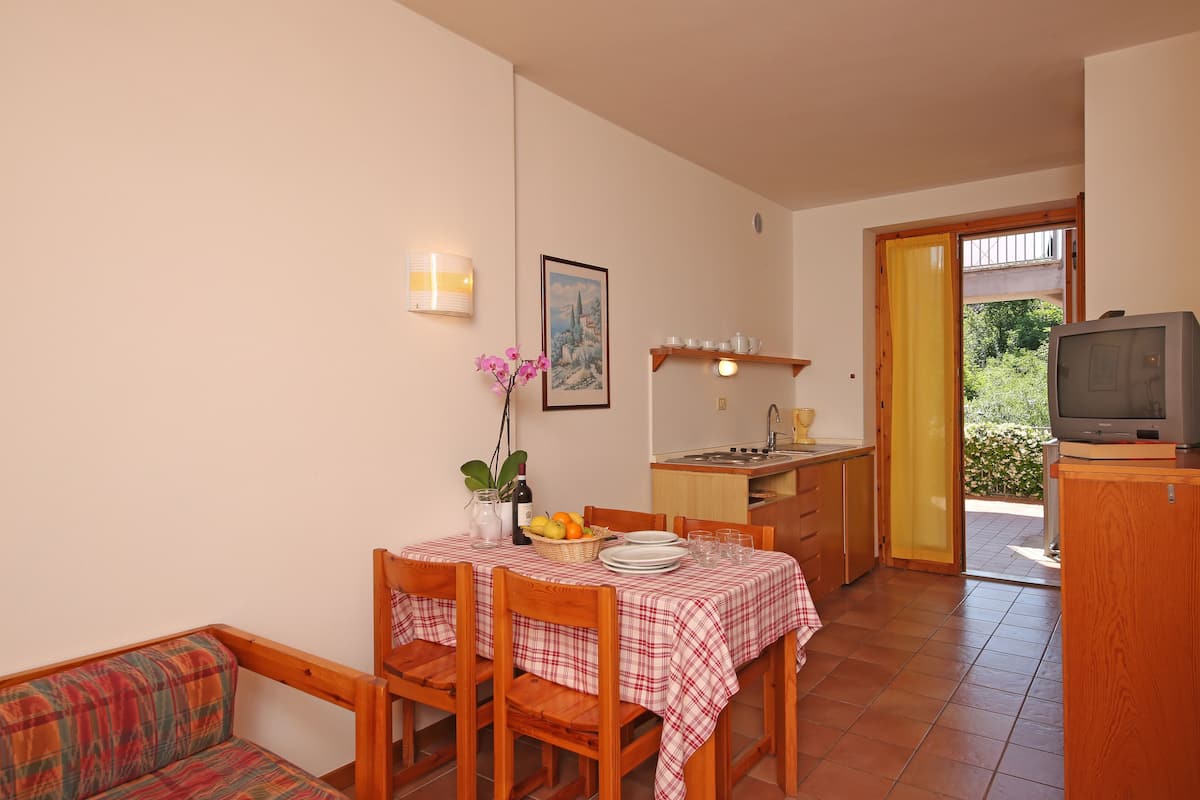A cozy dining area with a table set for two, a sofa, and a television in the corner.