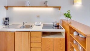Cocina moderna con armarios de madera, un lavamanos de acero inoxidable, una cafetera, un hervidor y una planta en maceta.