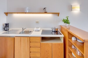Una cucina moderna con mobili in legno, lavello in acciaio inossidabile, macchina da caffè, bollitore e una pianta in vaso.