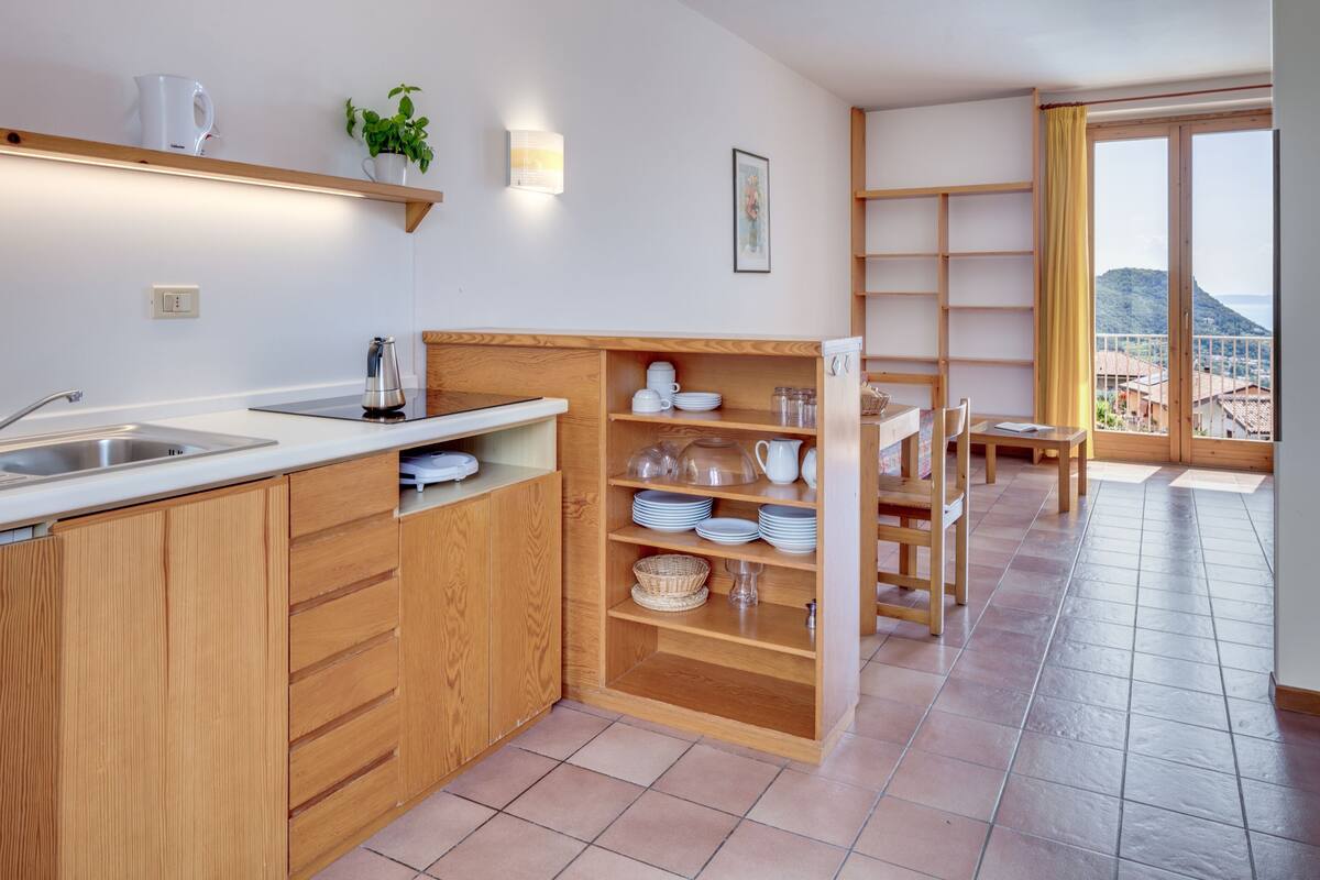 A modern kitchen with wooden cabinets, a sink, and a dining area with a table and chairs.