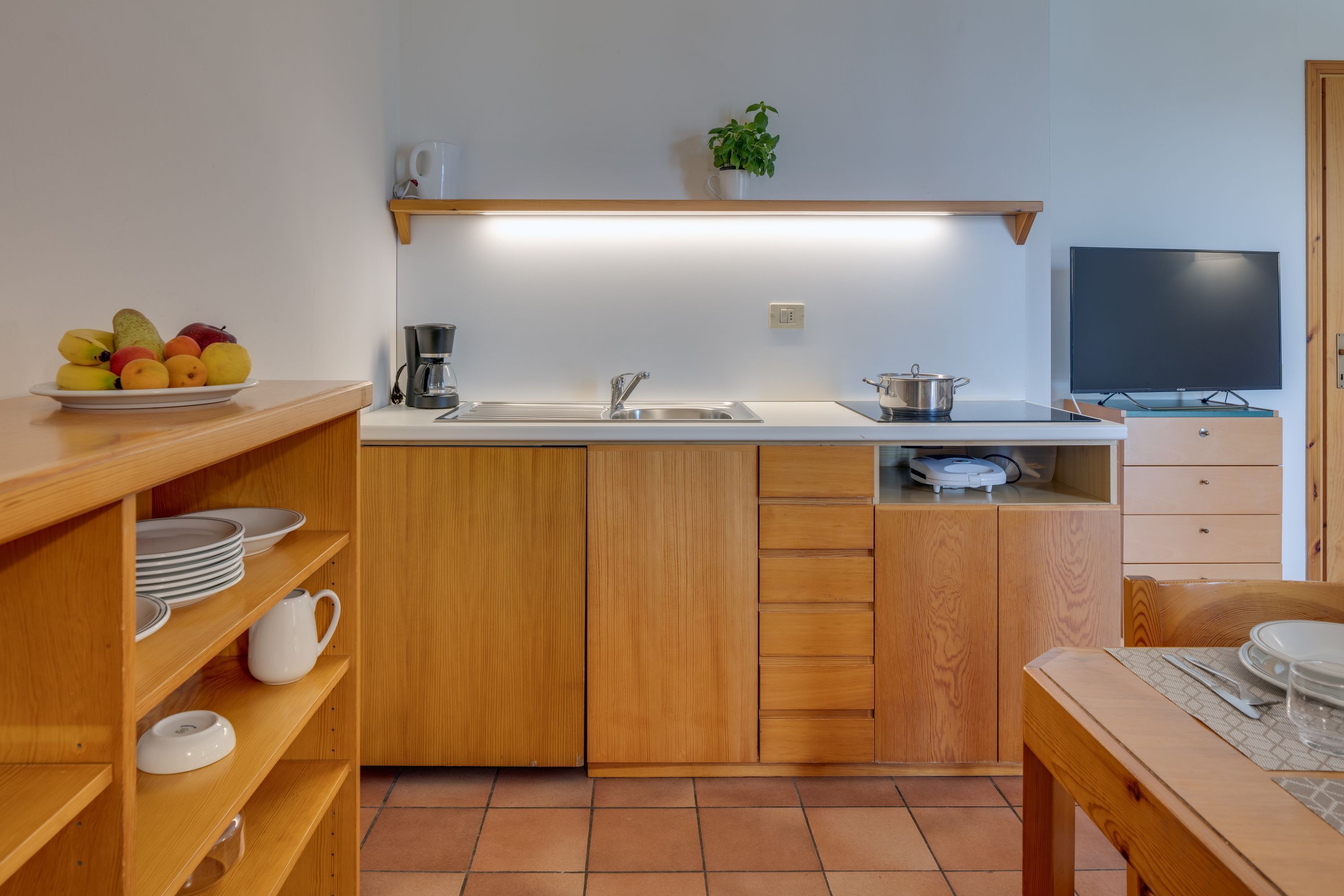 Une cuisine de taille réduite, équipée d’un évier, d’une cuisinière et d’un téléviseur.