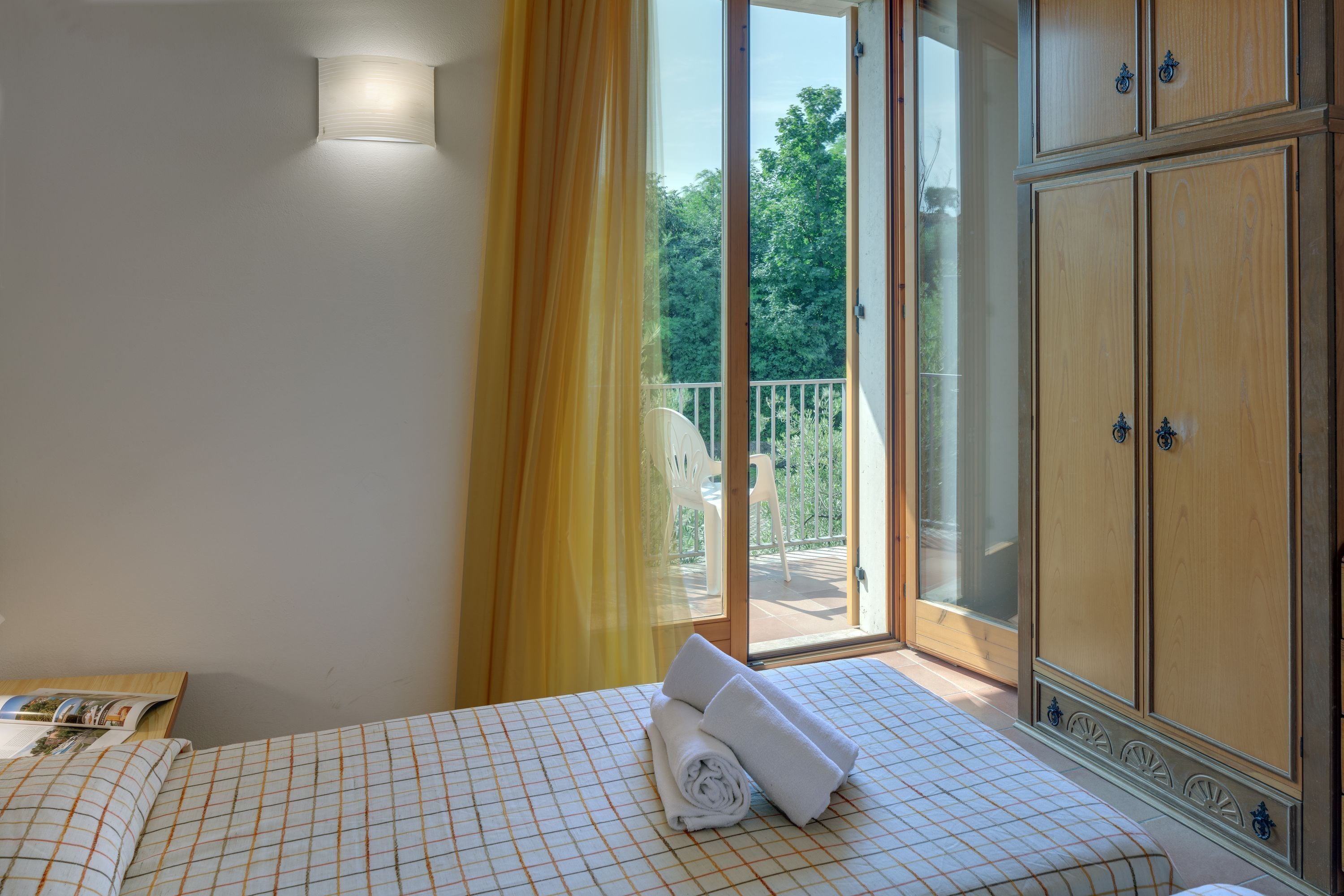 A bedroom with a bed, a wardrobe, and a sliding glass door leading to an outdoor area.